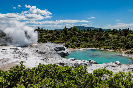 Geothermal activity shows steam escaping from a hot spring with a clear, turquoise pool