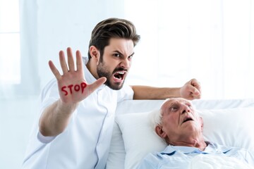 Obraz premium Senior Man Shows STOP as Abusive Male Caregiver Threatens Him