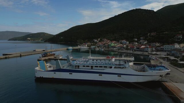 Ferry docked in a picturesque harbor, nestled against a backdrop of lush green hills and a charming coastal village.
