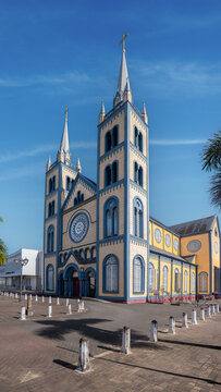 View of the Saint Peter and Paul Cathedral with its iconic yellow and blue wooden facade and twin spires under a clear blue sky in Paramaribo, Paramaribo District, Suriname.