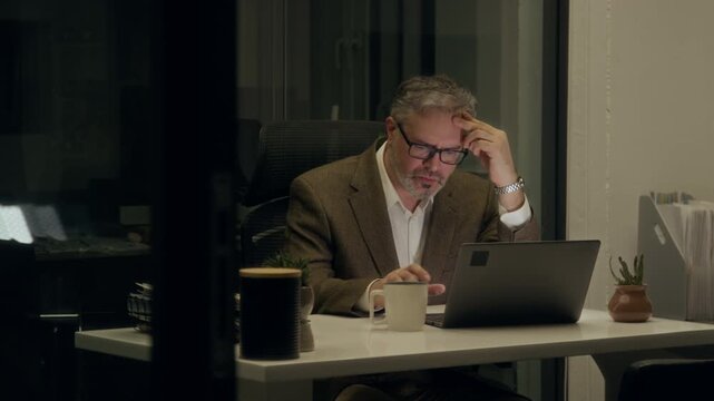 Medium shot of female colleague saying goodbye to exhausted workaholic male manager working overnight on project on laptop in dark office, patting on shoulder and urging to go home