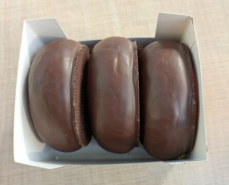 Vista de cerca de tres donuts cubiertos de chocolate en una caja de cart&oacute;n 
