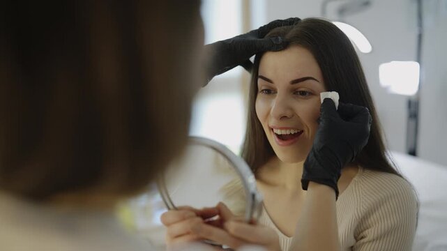 Client checking results after microblading eyebrow procedure