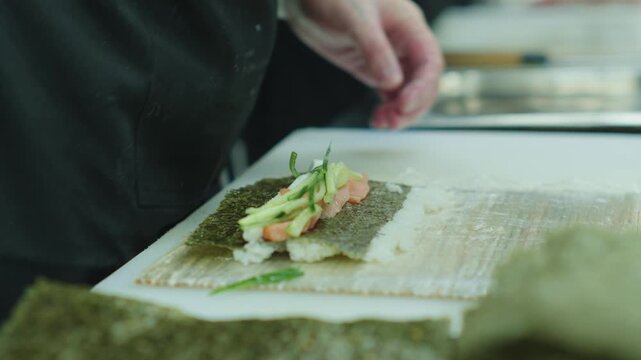 
A sushi chef rolls sushi ingredients. Japanese food. Sushi preparation.