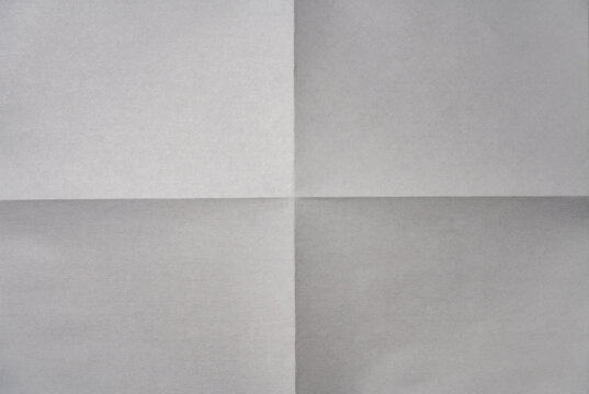 Minimalist background of white paper sheet folded into four quarters with sharp crease lines in the center. Top view of empty aged document texture