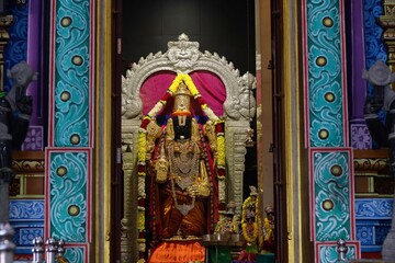 Fototapeta premium Intricately decorated and brightly lit Hindu deity shrine adorned with vibrant colors and flower garlands inside Batu Caves, Malaysia.