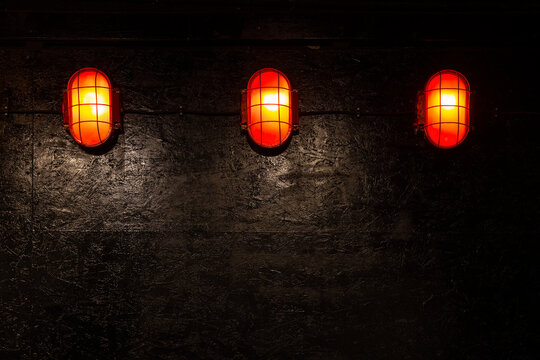 Three red glowing nautical lights on dark textured wall
