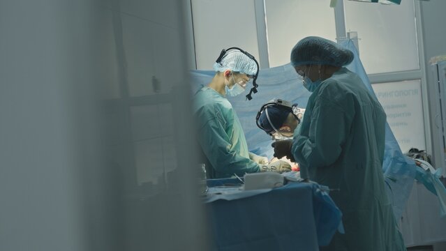 Surgery operating process medication of trauma three medics doctor with nurses assistants team cooperating in clinic hospital emergency surgical operation cardio heart neurosurgery surgeon saving life