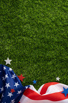 Draped vertical American flag and star decorations on fresh grass creating a patriotic background for Independence Day, Memorial Day and Labor Day outdoor celebrations and summer events