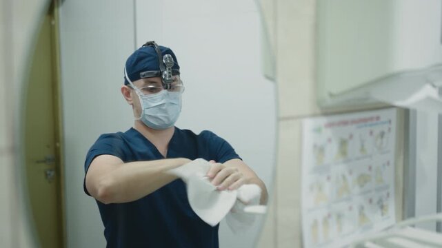 Mirror reflection view doctor man guy surgeon wipe hands with paper towel male practitioner sanitizing wiping arms with napkin surgery work in clinic lab hospital male in uniform medicine health job