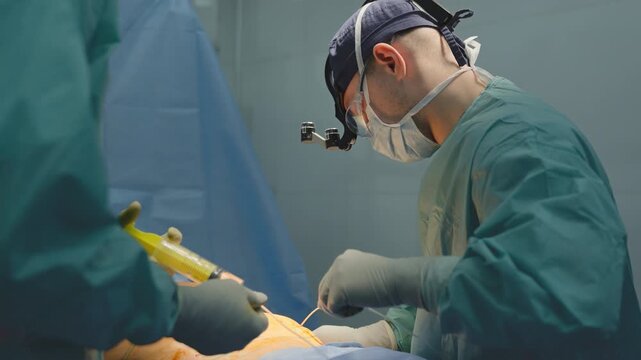 Professional surgeon doing medical operation in sterile hospital clinic operating room doctor man physician male working using surgical instruments health procedure with assistant medic cure medicine