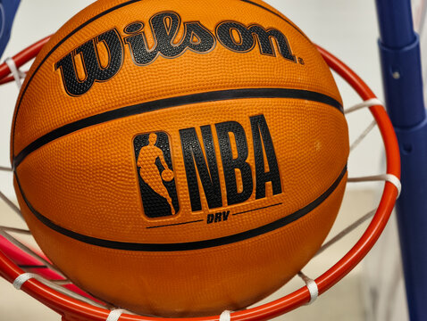 Prague, Czech Republic &ndash; March 31, 2026: Wilson NBA DRV basketball caught in hoop net with visible NBA logo and Wilson branding, close-up of official league ball on retail display in sporting goods 