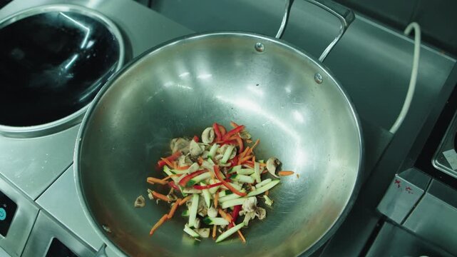 Frying vegetables in a hot iron deep frying pan. Asian cuisine. Wok frying.