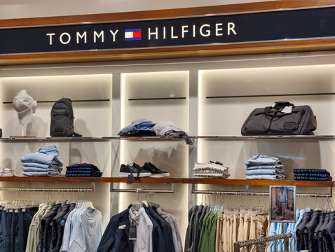 Prague, Czech Republic - March 31, 2026: Tommy Hilfiger retail display with illuminated logo, clothing racks, and accessories in a Prague store.