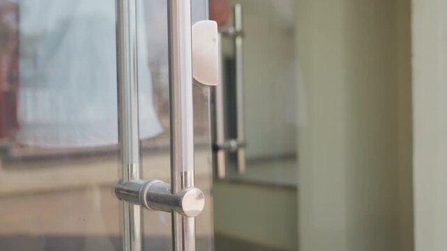 Black man inspecting glass house door during chores, cleaner checking handle and surface with cloth, focusing on hygiene and shine, stainless hardware, urban sidewalk background, daytime maintenance