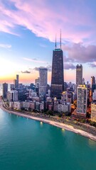 Obraz premium Vertical cityscape view of towers meeting a lake under a vibrant sunset sky