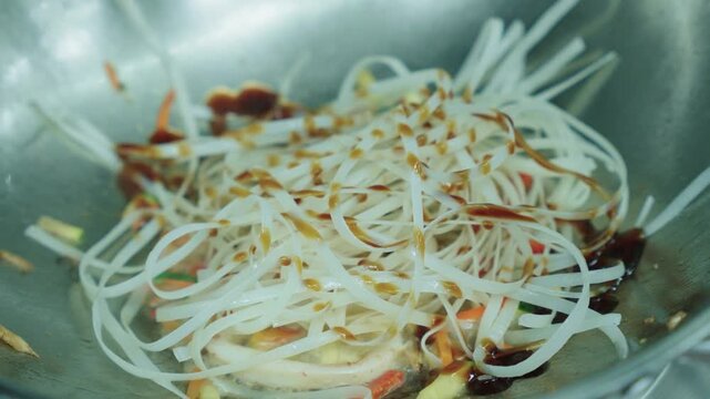 A cook stirs cooked noodles in a wok over a fire. Asian food. Cooking noodles. Stir-frying noodles with vegetables.