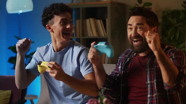 Happy father and his teen son celebrating a video game win with high five