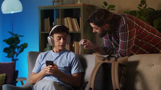 Angry father scolding his rebellious teen son for smoking marijuana at home