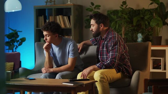 Middle-aged man consoling and supporting desperate teen son at home