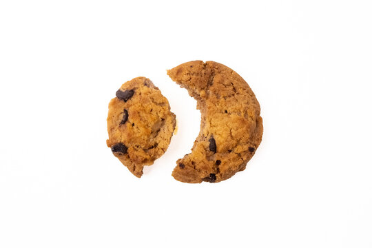 Top view of a chocolate chip cookie broken into two pieces, showing a large bite mark on a clean white background.