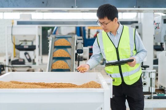 Factory quality inspector holding grain samples while checking product quality in a modern food processing facility