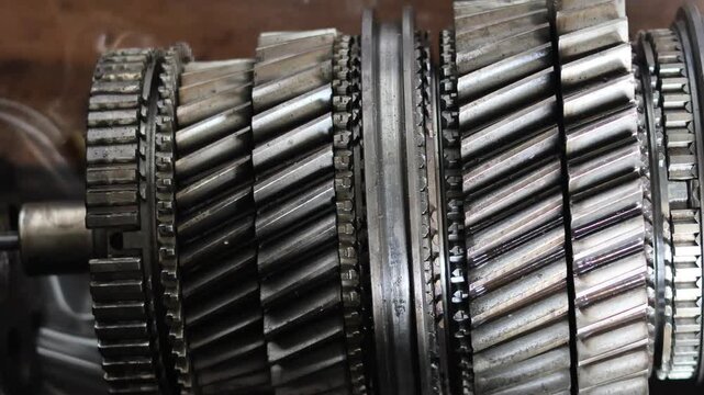 Close up panning shot of mechanical helical gears and synchronizer assembly inside a vehicle transmission system for industrial engineering and automotive repair.