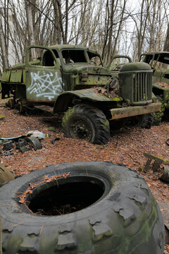 View of abandoned military trucks with graffiti and rusted parts in an overgrown forest area Pryp'yat', Kyiv Oblast, Ukraine.