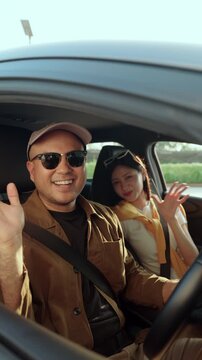 Happy young couple enjoying a road trip to the beach, driving car under blue sky. Travel in summer vacation, freedom lifestyle. Safe driving and joyful journey concept.
