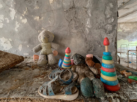 View of abandoned children's toys including a teddy bear and stacking rings on a dusty shelf in a derelict building in Pryp'yat', Kyiv Oblast, Ukraine.