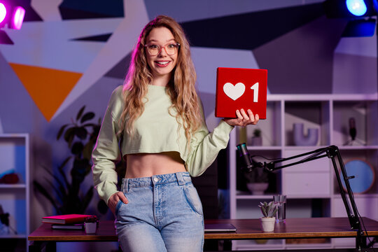 Young female internet blogger presenting online content in a creative workspace with modern decor and vibrant lighting