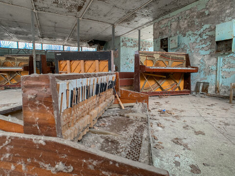View of abandoned and broken pianos with peeling paint on the walls in a derelict room in Pripyat, Kyiv Oblast, Ukraine.
