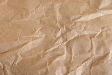 Fototapeta premium Crumpled Brown Kraft Paper Texture Background,Top view of wrinkled and crumpled brown kraft paper texture. A vintage, recycled paper background with organic creases and shadows, perfect for eco-friend
