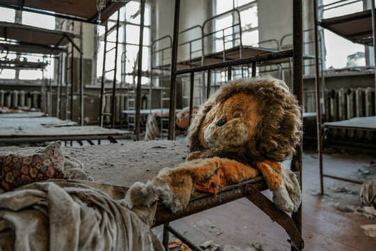 View of an abandoned dormitory with a dusty stuffed lion toy on a rusty metal bunk bed in Pryp'yat', Kyiv Oblast, Ukraine.