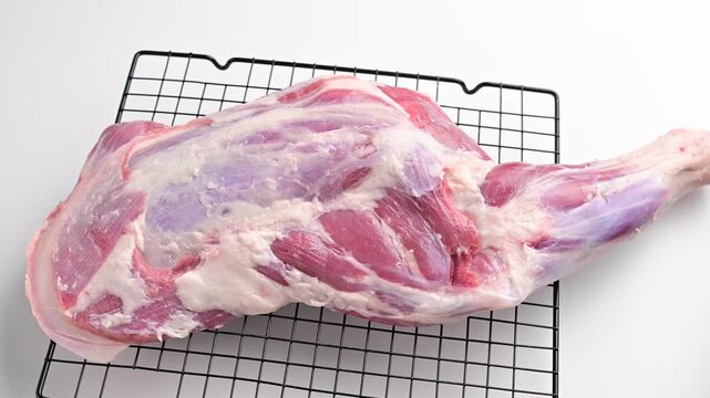 Exploring the preparation of pork meat on a cooling rack for cooking or curing in a clean kitchen space