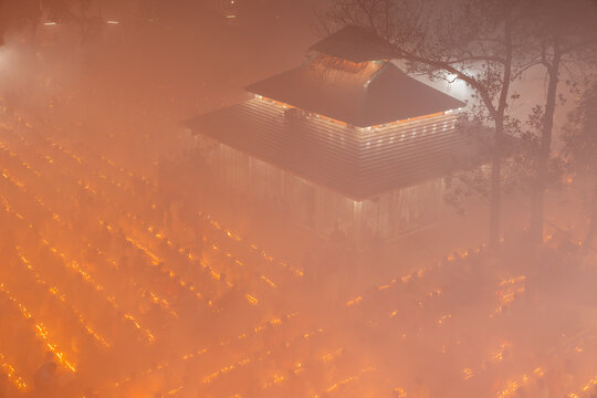 Baradi, Bangladesh - 09 November 2024: View of Sri Sri Loknath Bramhachari Shomadhi Mondir with devotees sitting in rows with lit oil lamps during Rakher Upabash festival in thick smoke.
