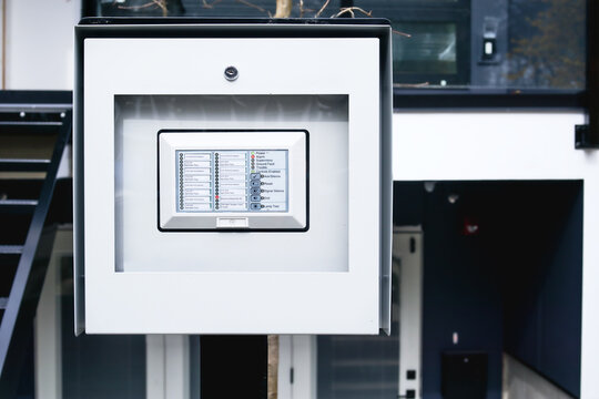 Outdoor fire alarm control panel or annunciator. Alarm activated. Red light in electrical room and problem. Waterproof and locked box with fire alarm annunciator. Fake unit labeling. Selective focus.