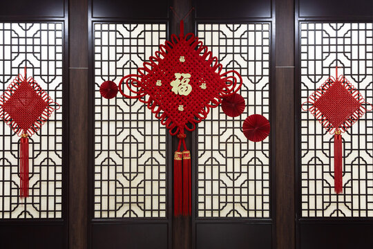 Traditional Chinese red knot decoration with fu character hanging in front of lattice window panels