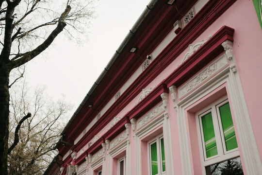 Colorful pink historic building facade with white decorative elements in Senta Serbia, showing vibrant architecture and urban cultural identity.