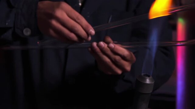 Artisan Rotating Glass Tube Over Gas Burner Flame in Neon Workshop, Close Up - 4K