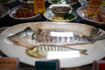 Sliced sea bass and saury fish served on a white platter in a restaurant setting © zhu difeng