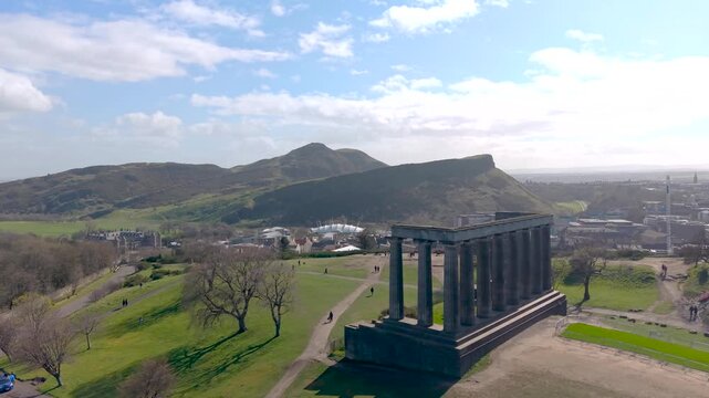 Cinematic Drone Orbit of Calton Hill Monuments at Daytime Edinburgh Skyline Arthur's Seat in Background Scotland