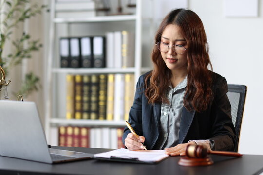 Female lawyer reviewing and signing a legal document while working on a case in her office.