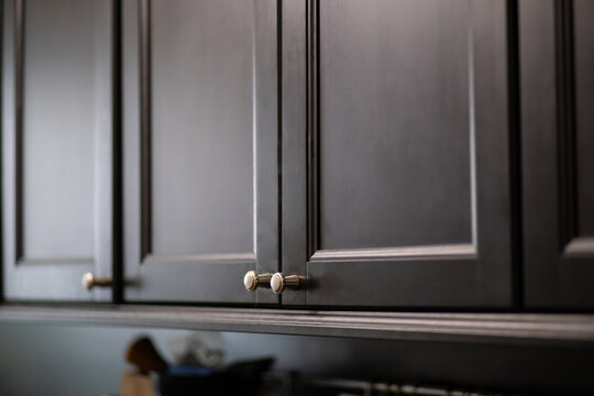 Modern dark cabinet doors with metal knobs. Stylish kitchen interior with matte black millwork. Minimalist design and home improvement concept for contemporary house renovation project.