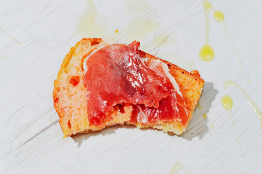 a bitten slice of pa amb tomaquet with ham