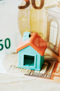 a toy house placed over a euro banknote