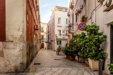 Fototapeta premium Charming narrow street decorated with flowers of picturesque Monopoli old town, Puglia, Italy