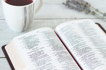 Fototapeta premium Holy bible book with cup of tea on wooden background. Selective focus. Christian thanksgiving to God Jesus Christ, Scripture study concept.