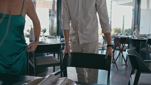 Luxury dining lifestyle with man pulling out chair for elegant woman. Romantic date scene with chivalry, etiquette and fine dining experience in upscale restaurant.