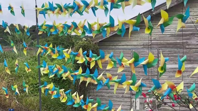 Rows of small decorative colorful pinwheels spinning rapidly during a windy day at Titi Village landmark in Negeri Sembilan Malaysia in January 2025.